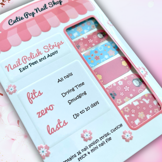 Neko nail polish strips by Cutie Pop Nail Shop featuring light pink and light blue designs with cherry blossom sakura patterns, gold foil accents, and cute anime-inspired art including cats, bunnies, and kawaii Japanese motifs arranged on a pink edged display card labeled "Easy Peel & Apply Nail Strips."