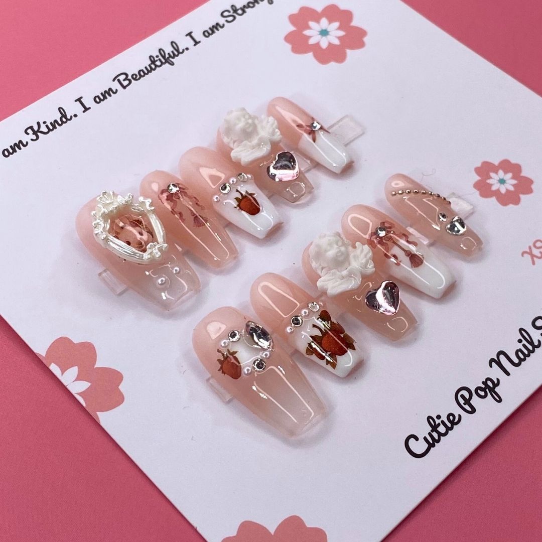 Angelic Bunny press on nails by CutiePop Nail Shop featuring medium coffin shaped nails in soft pastel tones, adorned with bunny charms, angel wings, and pearl or glitter details for a cute and dreamy aesthetic.