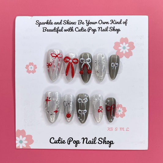 Bowtique Sparkle press‑on nails by CutiePop Nail Shop featuring a medium‑length almond‑shaped set coated in vibrant rose‑pink glitter polish, accented with dainty 3D bow-shaped charms and sparkling rhinestones, giving a flirty, playful yet glamorous aesthetic.