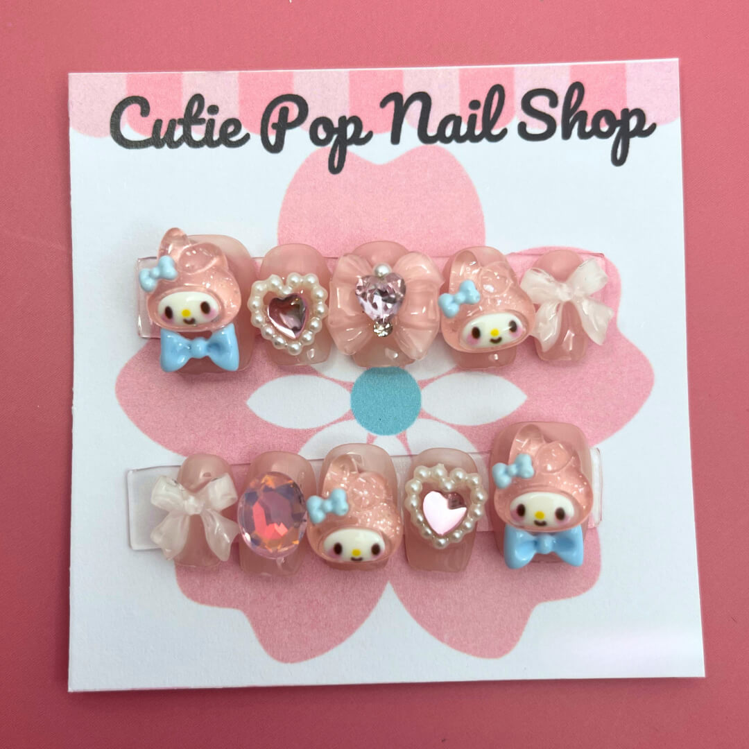 Bunny Pink Bow press on nails by CutiePop Nail Shop featuring short or medium coffin shaped nails in soft pink tones, adorned with adorable bunny motifs, dainty bow accents, and subtle glitter details. Designed for a sweet, playful look with a kawaii charm. Includes a full DIY kit with 10 reusable handmade nails, jelly adhesive tabs, a mini nail file, and a cuticle stick.