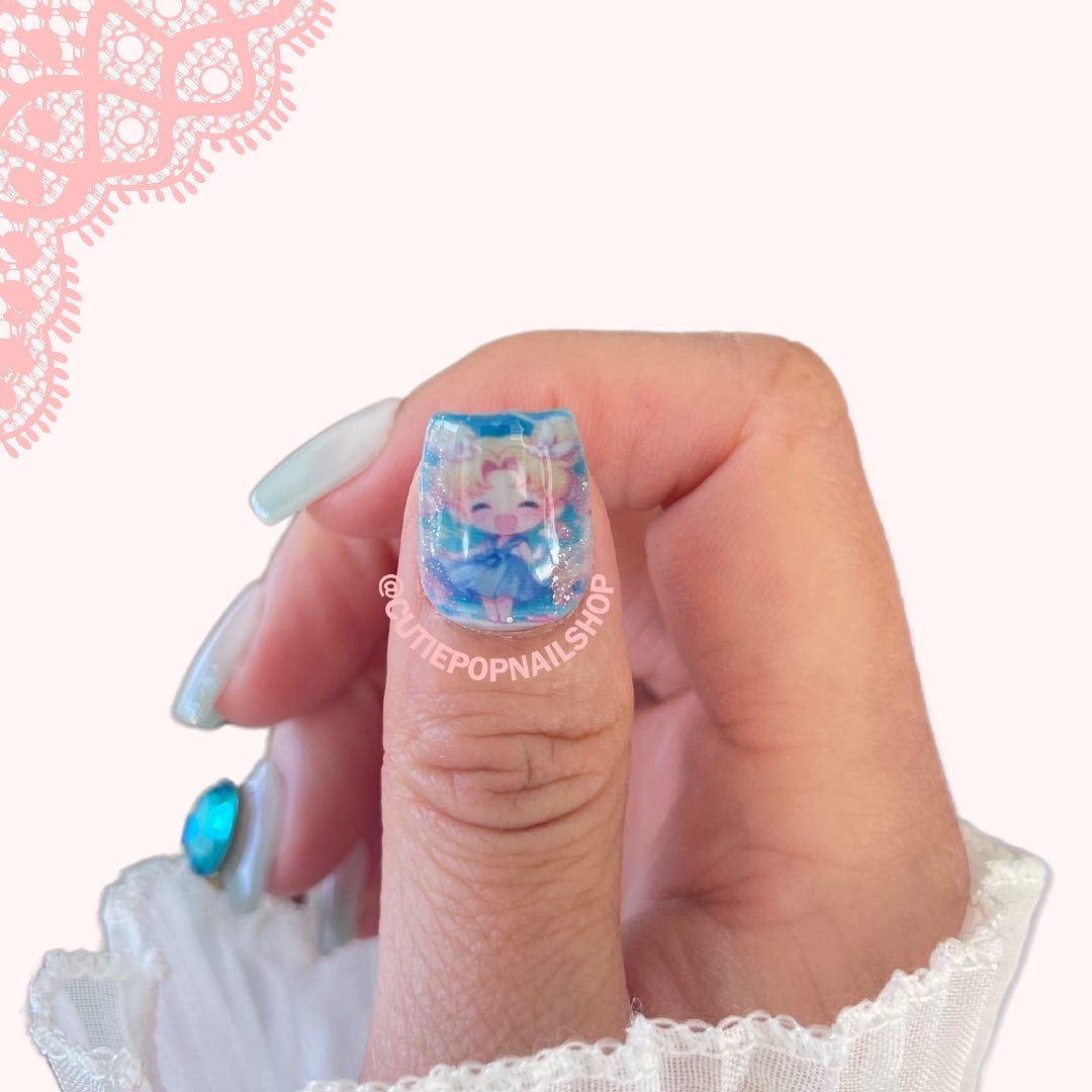 Moon Prism press‑on nails by CutiePop Nail Shop featuring medium-length square-shaped nails with a sheer, pastel pink-to-lavender jelly gradient and iridescent holographic sparkle. Accented with delicate hand‑placed star glitter, tiny crescent moon charms, and subtle metallic flake shimmer—delivering a dreamy, celestial-inspired manicure perfect for magical girl or Y2K aesthetic lovers. Kit includes ten reusable nails, adhesive tab sheet, a mini nail file, and a cuticle stick.