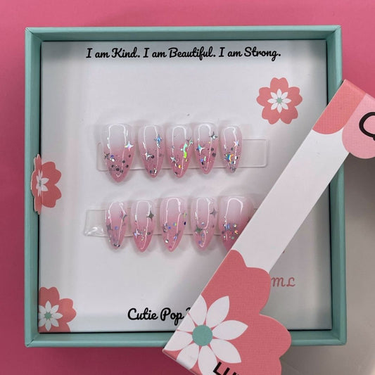 Fantasy (Blush) press-on nails by CutiePop Nail Shop featuring medium-length almond-shaped nails in soft blush pink tones. Designed with dreamy elements like pearls, subtle shimmer, and delicate accents, this set evokes a whimsical, fairy-like aesthetic. Comes with 10 reusable handmade nails, jelly adhesive tabs, a mini nail file, and a cuticle stick for easy at-home application.