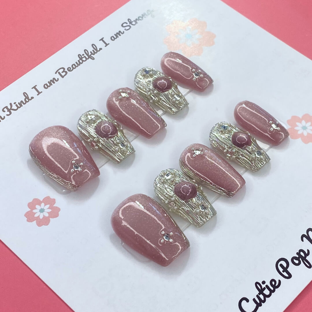 Gold Rosey press on nails by CutiePop Nail Shop featuring medium coffin shaped nails in a luxurious mix of rose gold and warm golden hues, enhanced with hand sculpted 3D gel accents and subtle metallic shimmer for an elegant and glamorous aesthetic.