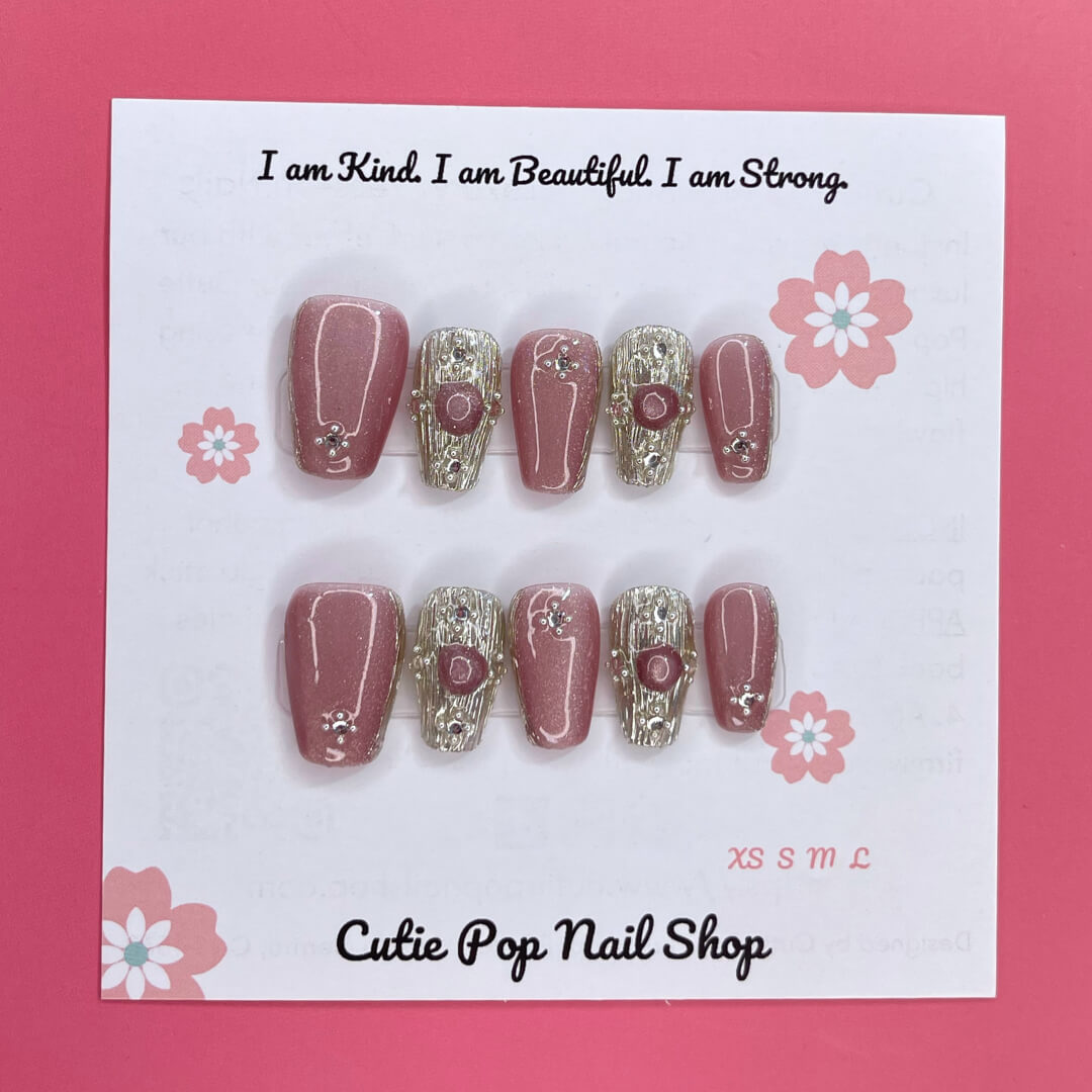 Gold Rosey press on nails by CutiePop Nail Shop featuring medium coffin shaped nails in a luxurious mix of rose gold and warm golden hues, enhanced with hand sculpted 3D gel accents and subtle metallic shimmer for an elegant and glamorous aesthetic.