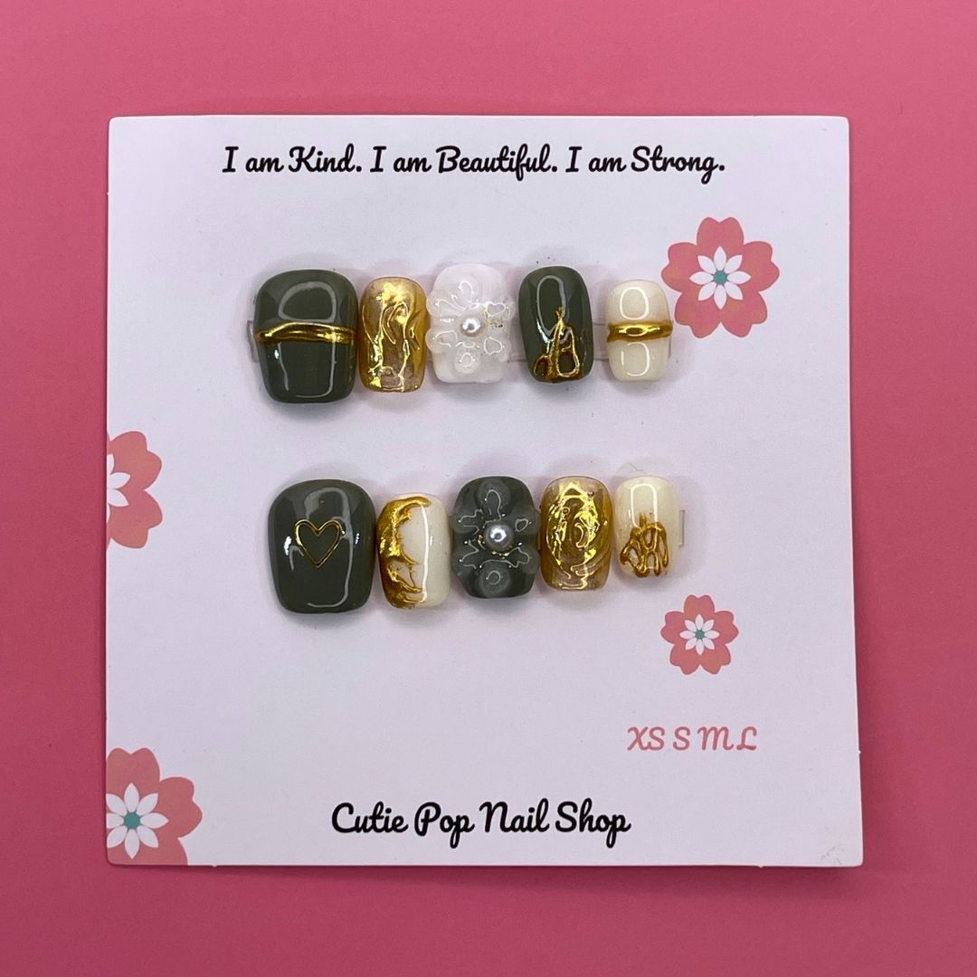 Golden Lady press-on nails by CutiePop Nail Shop featuring short squoval-shaped nails in elegant nude and gold tones, adorned with metallic accents and fine glitter for a luxurious, feminine finish.