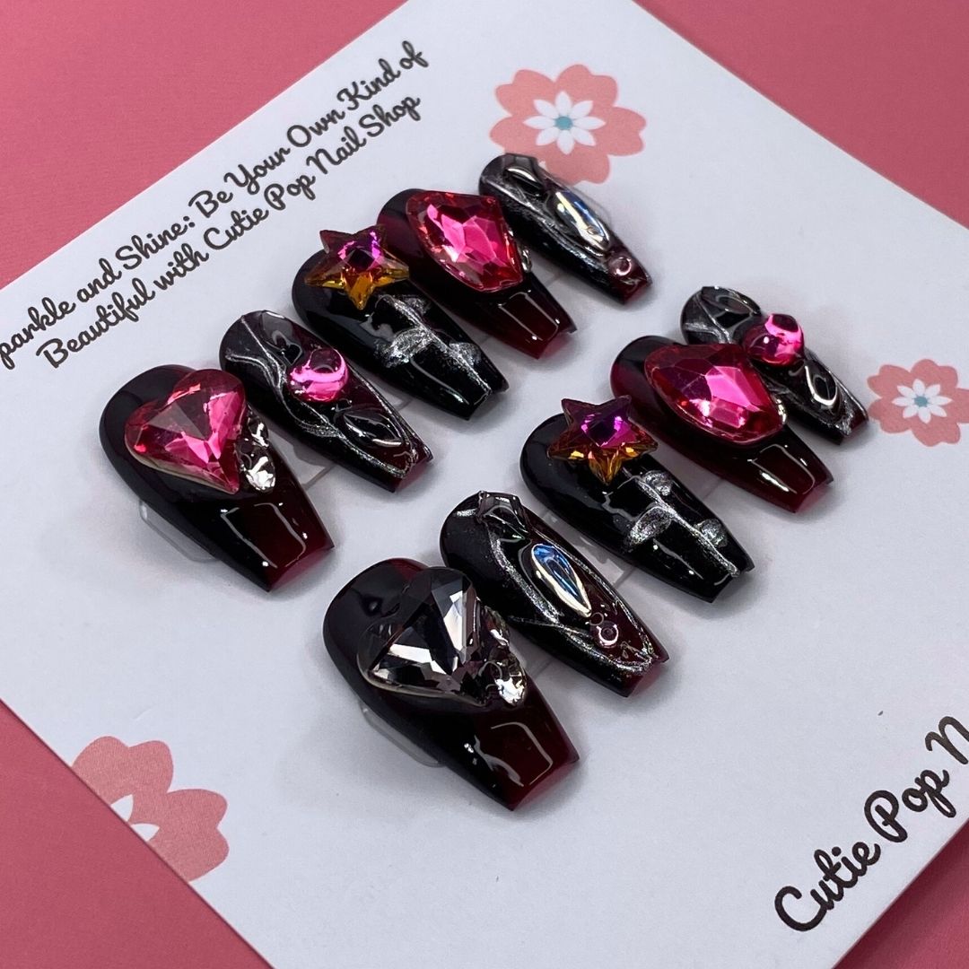 Gothic Ruby press-on nails by CutiePop Nail Shop featuring medium-length coffin-shaped nails in deep red and black tones, adorned with ornate gothic patterns and gemstone accents. This dark, elegant design channels vintage luxury and dramatic flair—perfect for a bold statement manicure.