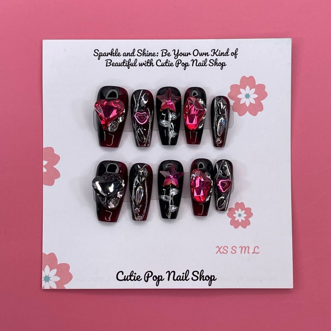 Gothic Ruby press-on nails by CutiePop Nail Shop featuring medium-length coffin-shaped nails in deep red and black tones, adorned with ornate gothic patterns and gemstone accents. This dark, elegant design channels vintage luxury and dramatic flair—perfect for a bold statement manicure.