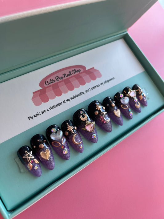 Cosmic Moon – Saturn press on nails by CutiePop Nail Shop featuring medium almond shaped nails with a hand painted black to purple ombré, finished in high reflective fine glitter gel polish. Inspired by Sailor Moon aesthetics, this dramatic celestial design is topped with a glossy shine for an enchanting, spacey effect.