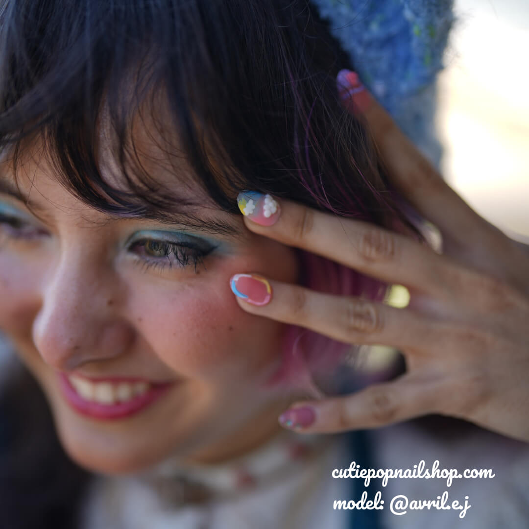 Kawaii Bunny Pastel Rainbow press-on nails by CutiePop Nail Shop featuring medium-length round/oval nails in a mix of soft pastel hues—baby pink, lavender, mint green, and pale yellow—with whimsical hand-painted bunny faces, cloud and rainbow motifs, heart and star accents over a dreamy gradient. Comes as a full DIY-ready kit including ten reusable handmade nails, jelly adhesive tabs, a mini nail file, and a cuticle stick—perfect for a bright, cute-and-playful kawaii-inspired manicure.