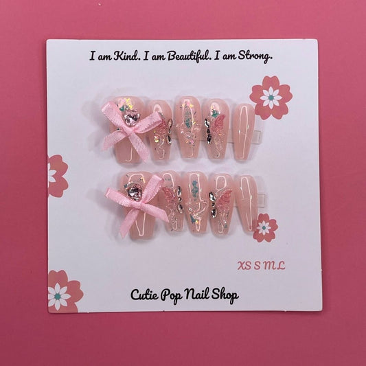 Lovely Butterfly press on nails by CutiePop Nail Shop featuring medium coffin shaped nails with a soft pastel base, adorned with a large 3D butterfly charm and delicate ribbon accents—designed for a dreamy and feminine look.