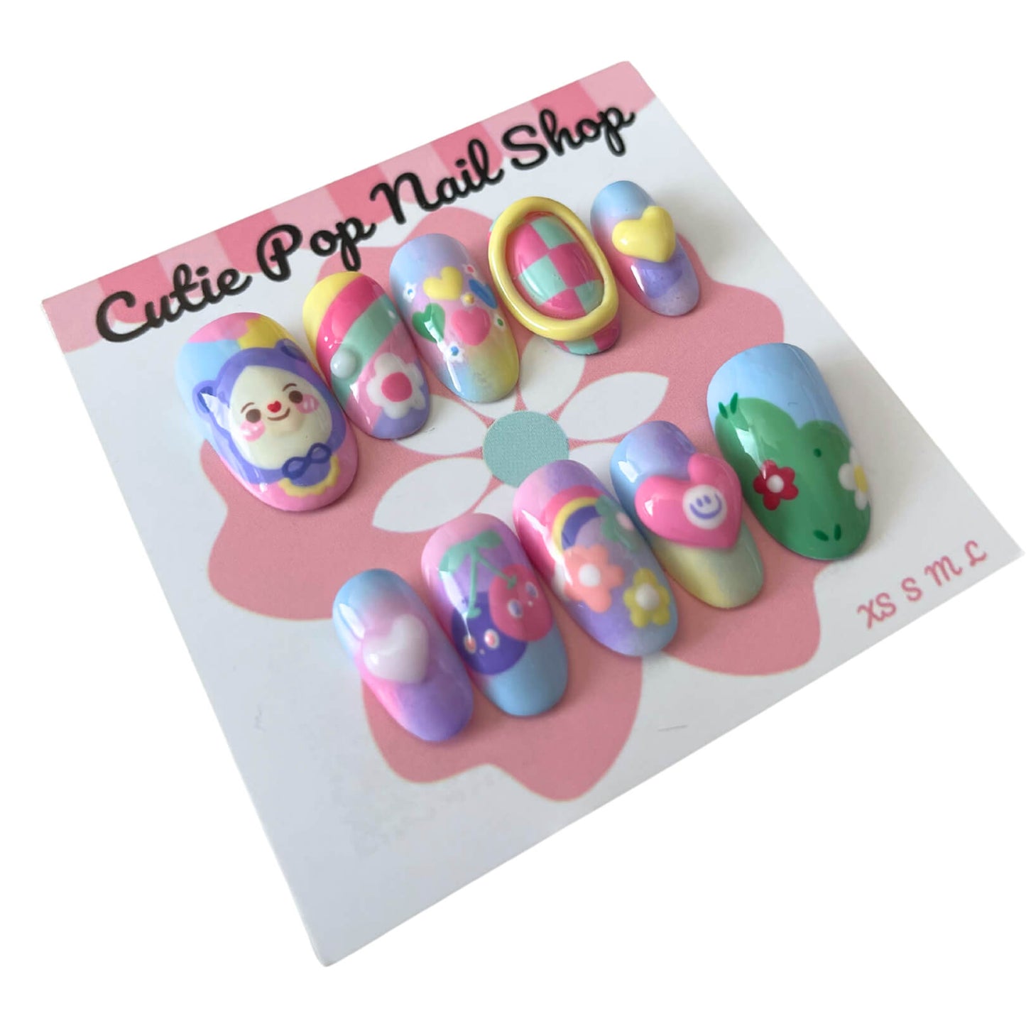 Pastal Friends press‑on nails by CutiePop Nail Shop showcasing a fun round-shaped, short-length set in soft pastel hues—featuring hand-painted cherries, charming hearts, cheerful flowers, and a cute doll motif on alternating nails. Includes the full reusable kit with adhesive tabs, mini file, and cuticle stick for a whimsical, kawaii‑inspired look.