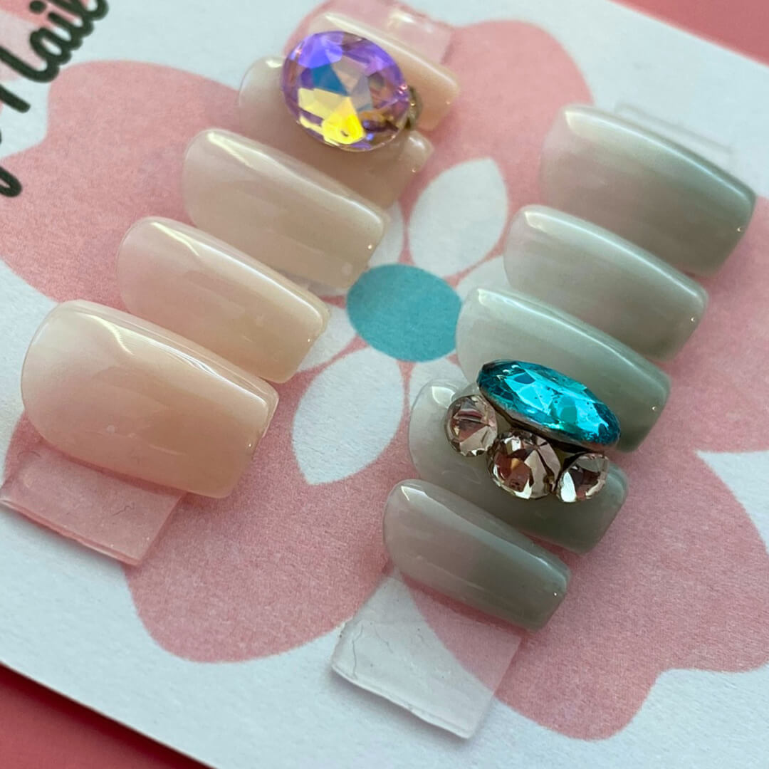 Pastel Gem press‑on nails by CutiePop Nail Shop featuring short, square-shaped nails in soft pastel hues—including blush pinks, mint green, and lavender—adorned with oversized iridescent gem embellishments and subtle metallic accents. Includes a reusable set with adhesive tabs, a mini nail file, and a cuticle stick, offering a sweet, dreamy manicure with a touch of luxe sparkle.