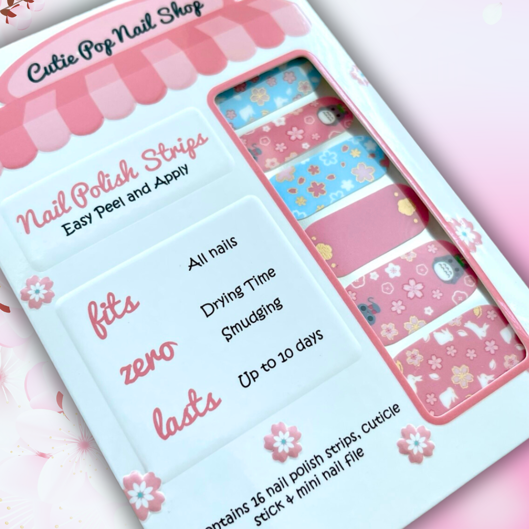 Neko nail polish strips by Cutie Pop Nail Shop featuring light pink and light blue designs with cherry blossom sakura patterns, gold foil accents, and cute anime-inspired art including cats, bunnies, and kawaii Japanese motifs arranged on a pink edged display card labeled "Easy Peel & Apply Nail Strips."