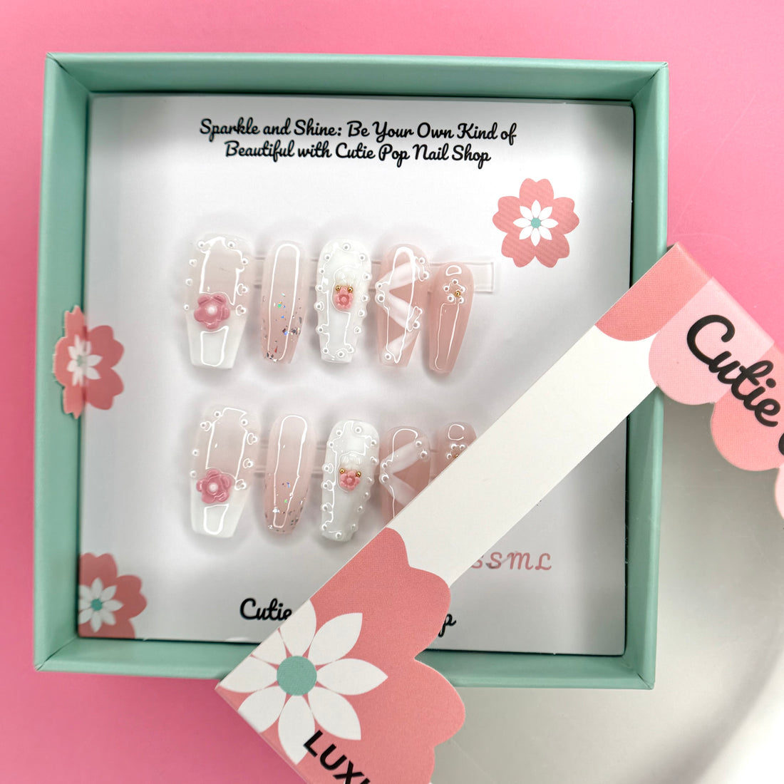 White Ribbon Pink Flower press-on nails by CutiePop Nail Shop featuring medium-length coffin-shaped nails in soft pink tones. Embellished with pearl accents, white ribbon details, and delicate pink floral designs, this set offers a sweet and feminine aesthetic perfect for elegant everyday wear.

