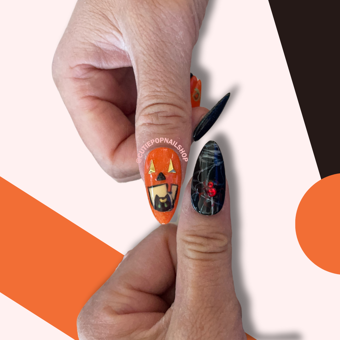 Pumpkin Cat Nails (Size SMALL) press‑on nails by CutiePop Nail Shop featuring medium-length almond-shaped nails in a vivid orange and deep black palette. These Halloween-themed nails showcase hand-drawn pumpkin faces with adorable black cats nestled inside their grinning mouths, accented by tiny spider motifs (one with a red rhinestone body), cat-eye polish finish, and a dainty heart charm. Comes as a complete reusable kit with ten handmade nails sized at 15‑11‑12‑11‑9.5 mm (thumb to pinky), plus adhesive t