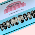 Black Butterfly press on nails by CutiePop Nail Shop featuring short length coffin shaped nails in a glossy jet black base. Several accent nails display clear backgrounds with bold black butterfly wing decals and metallic silver stud embellishments. Includes a full reusable kit: ten handmade nails, jelly adhesive tabs, mini nail file, and cuticle stick—offering a modern, edgy butterfly goth aesthetic.