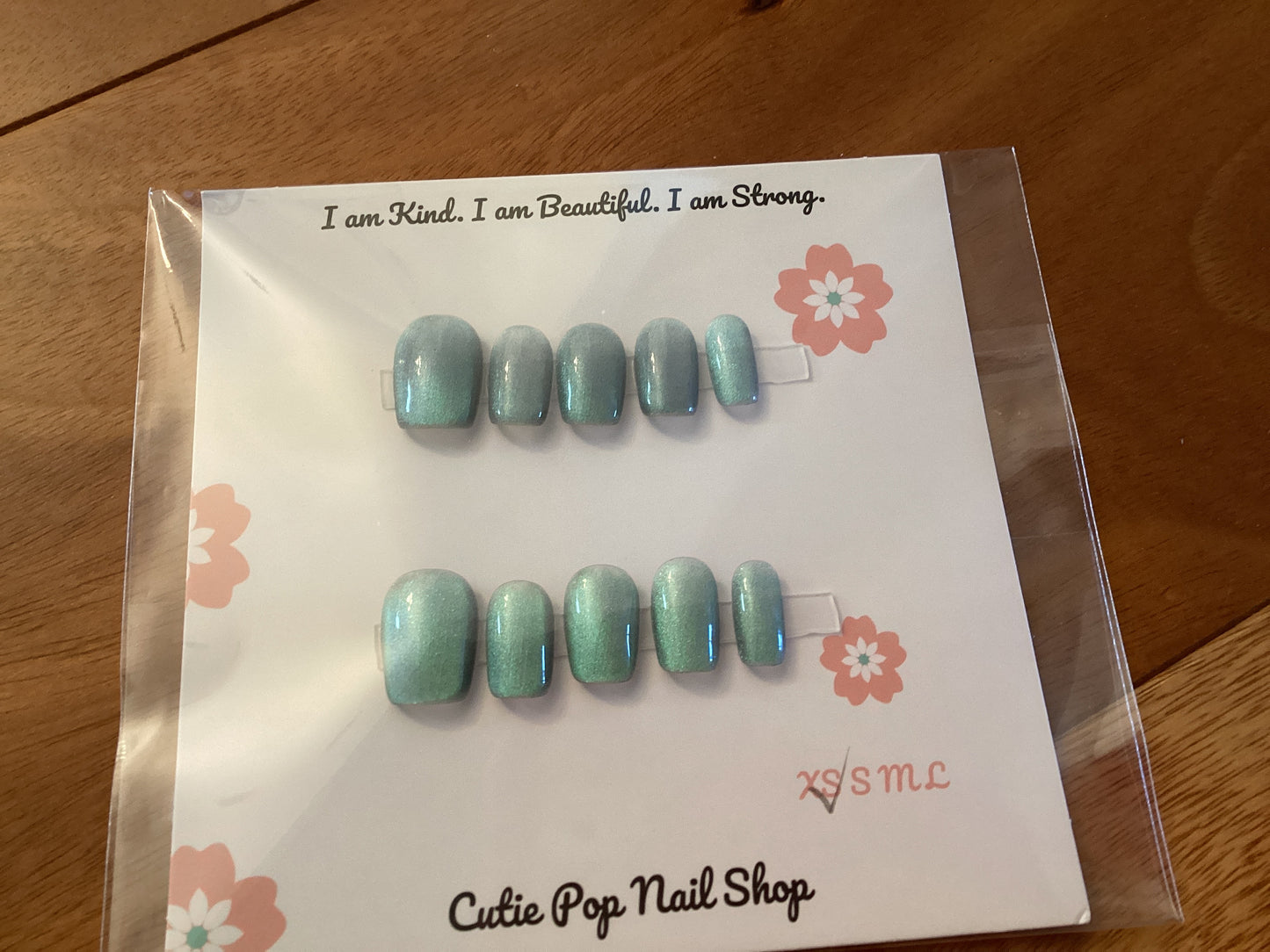 Cat’s Eye Ivory press-on nails in a soft ivory base with light blue shimmer and a glossy finish – displayed on a Cutie Pop Nail Shop card.