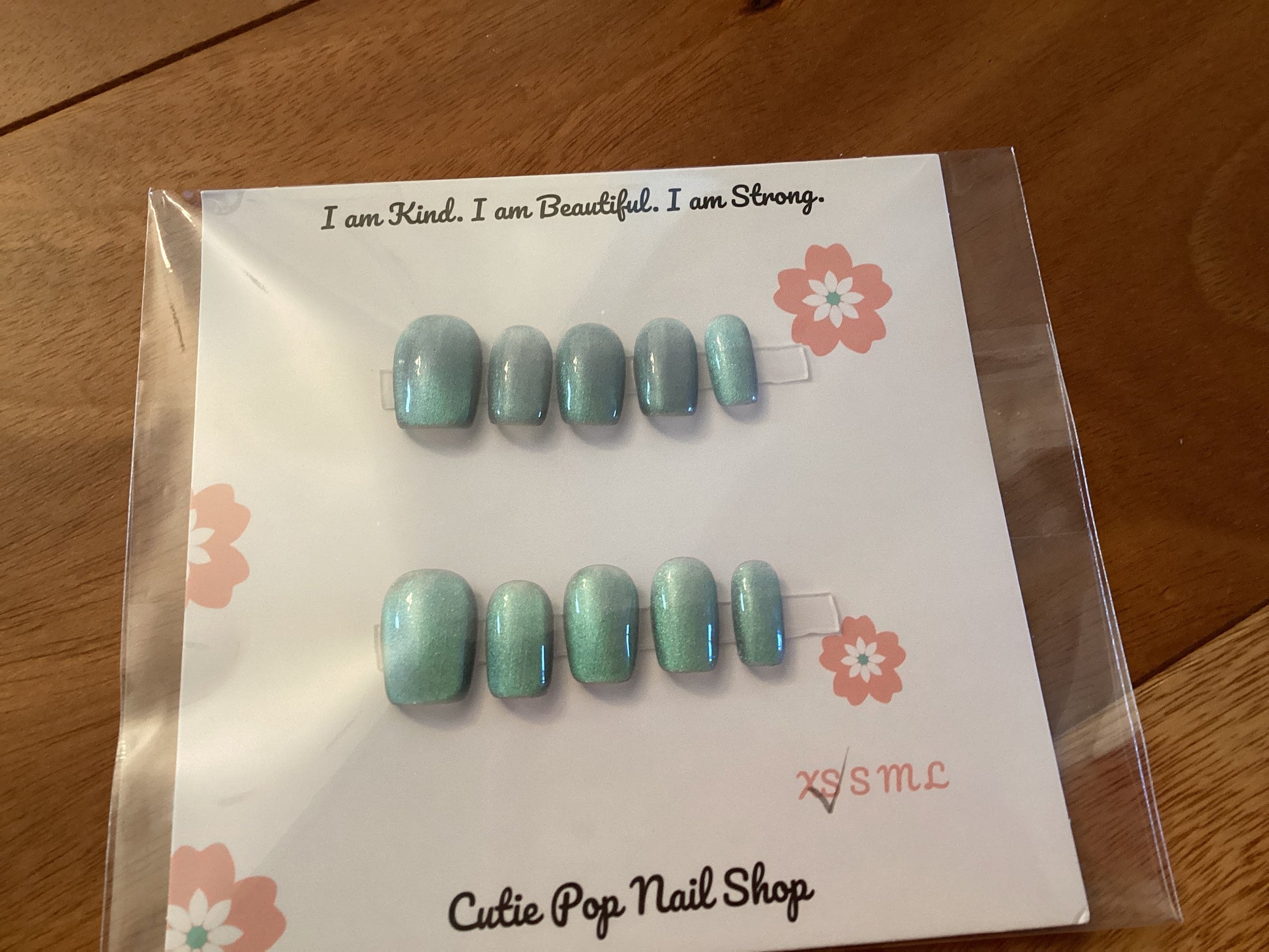 Cat’s Eye Ivory press-on nails in a soft ivory base with light blue shimmer and a glossy finish – displayed on a Cutie Pop Nail Shop card.