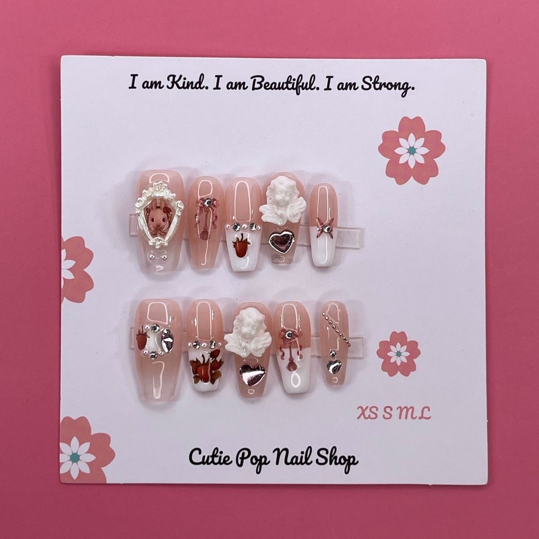 Angelic Bunny press on nails by CutiePop Nail Shop featuring medium coffin shaped nails in soft pastel tones, adorned with bunny charms, angel wings, and pearl or glitter details for a cute and dreamy aesthetic.

