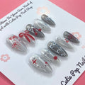 Bowtique Sparkle press‑on nails by CutiePop Nail Shop featuring a medium‑length almond‑shaped set coated in vibrant rose‑pink glitter polish, accented with dainty 3D bow-shaped charms and sparkling rhinestones, giving a flirty, playful yet glamorous aesthetic.