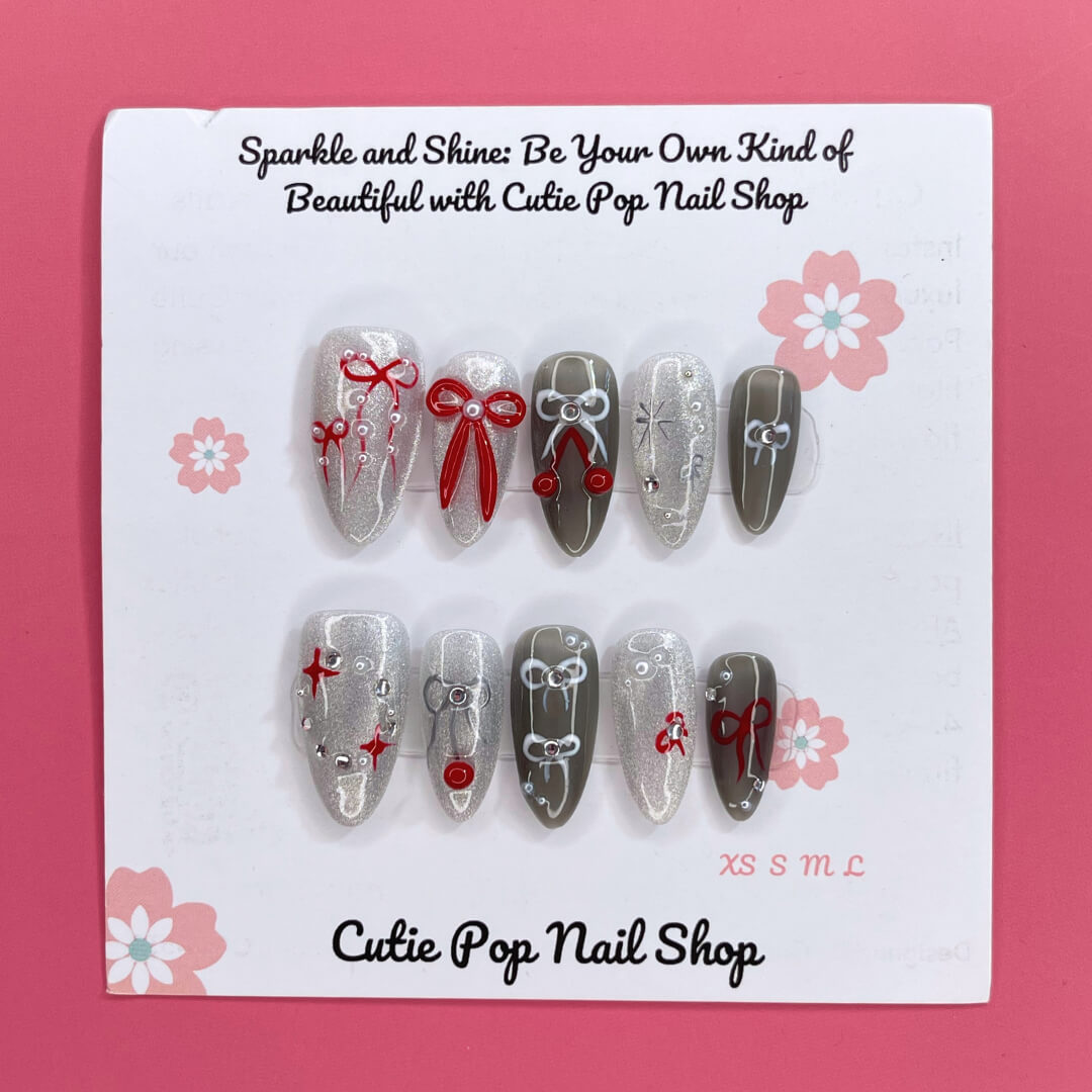 Bowtique Sparkle press‑on nails by CutiePop Nail Shop featuring a medium‑length almond‑shaped set coated in vibrant rose‑pink glitter polish, accented with dainty 3D bow-shaped charms and sparkling rhinestones, giving a flirty, playful yet glamorous aesthetic.