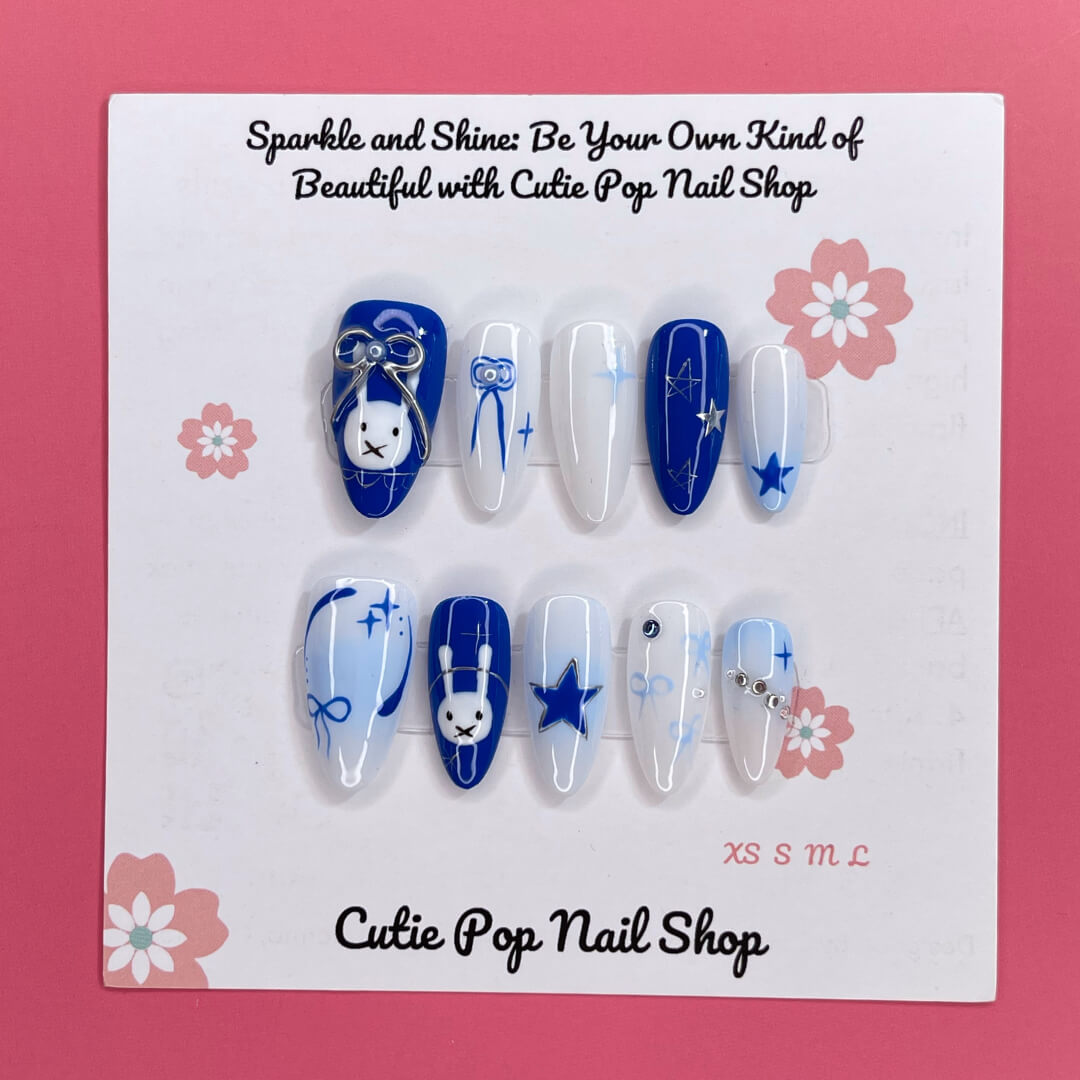 Bunny Starlight press‑on nails by CutiePop Nail Shop featuring a playful mix of glossy royal blue and clean white almond‑shaped nails, accented with hand-painted bunny motifs, delicate bow ribbons, and shimmering star charms—creating a whimsical, dreamy aesthetic perfect for kawaii-inspired looks.