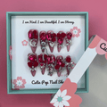 Bougie Bling 11 press on nails by CutiePop Nail Shop featuring long stiletto shaped nails with a bold wine red glitter base layered with luxurious oversized 3D gem clusters in deep jewel tones, accented with sparkling rhinestones and metallic detailing. Hand sculpted for a dramatic, upscale statement mani.