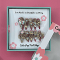 Bougie Bling 12 press on nails by CutiePop Nail Shop featuring long stiletto shaped nails with a glamorous deep dark burgundy or smoky wine toned glitter base. Lavish oversized 3D gem clusters in jewel tones such as ruby and crystal are complemented by sparkling rhinestones and metallic accents—arranged in an opulent, high impact luxury statement manicure.

