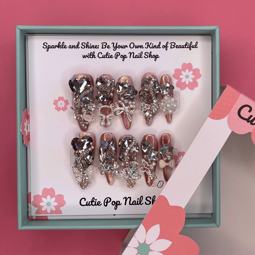 Bougie Bling 14 press on nails by CutiePop Nail Shop featuring long stiletto shaped nails with a dramatic glossy black base adorned with sparkling silver glitter accents and glamorous oversized 3D gem clusters in clear, smoke, and metallic tones, meticulously arranged for a bold, luxurious statement manicure.