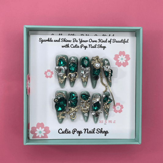 Bougie Bling 15 press on nails by CutiePop Nail Shop showcasing long coffin shaped nails with a dramatic glittery black base embellished with oversized 3D gem clusters in jewel tones, delicate rhinestone accents, and metallic detailing—all arranged in an ornate, high-impact luxury statement manicure.