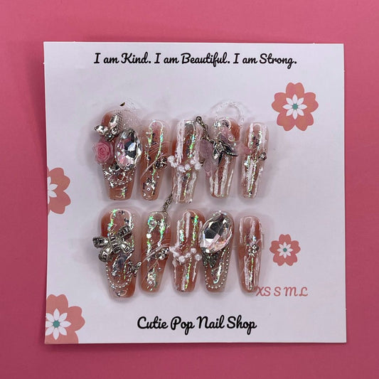 Bougie Bling 19 press on nails by CutiePop Nail Shop showcasing long coffin shaped nails with a luxe metallic rose gold base, oversized 3D gem clusters, sparkling rhinestone accents, and hand sculpted detailing—offering a glamorous, high end aesthetic.