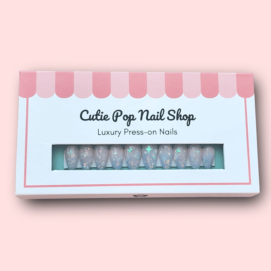 Fantasy (Lavender) press‑on nails by CutiePop Nail Shop featuring short-to-medium length almond-, round-, or coffin-shaped nails coated in dreamy lavender syrup jelly gel polish. Each nail is sprinkled with holographic star sequin glitter for a celestial shimmer effect. The set includes ten handmade reusable nails, jelly adhesive tabs, a mini nail file, and a cuticle stick—offering a whimsical, fantasy-inspired manicure perfect for summer enchantment.