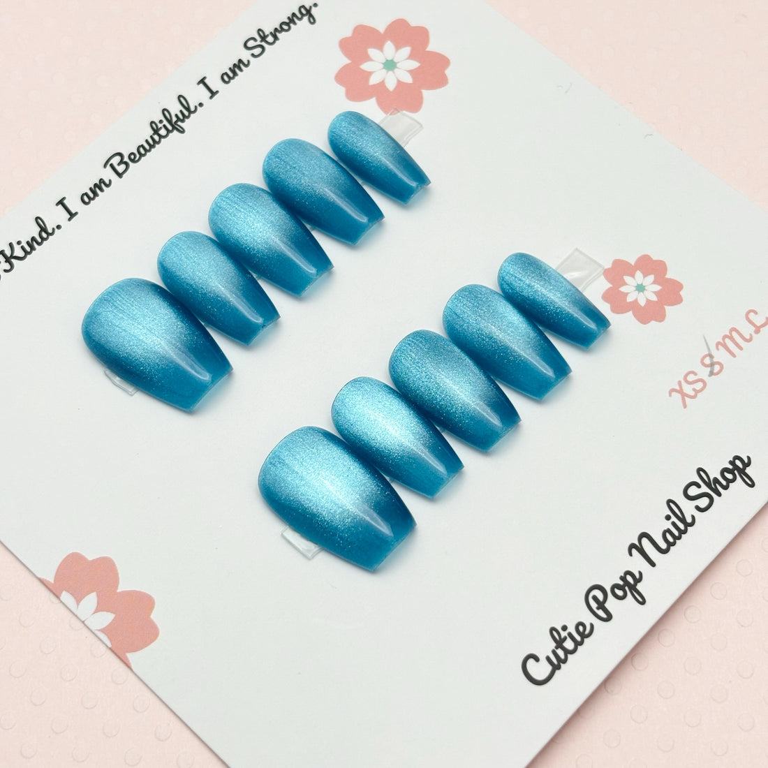 Set of blue aqua presson nails on Cutie Pop Nail Shop branded card with motivational quote and floral designs.ua