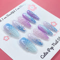 Enchanted Ombre press on nails by CutiePop Nail Shop featuring long stiletto shaped nails with a dreamy pastel ombré blend of icy blue, lavender, and soft pink tones. Accented with chunky glitter, sparkling gems, and intricate embossed details—finished in a glossy coat for a magical, whimsical aesthetic.

