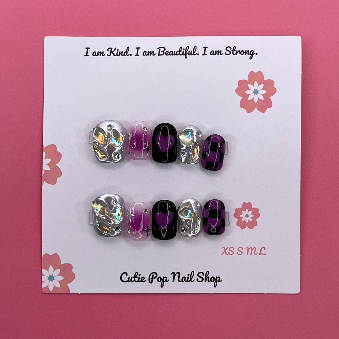 Galaxy Beauty press-on nails by CutiePop Nail Shop featuring extra short squoval-shaped nails in a cosmic blend of deep blue, purple, and black tones, accented with shimmering stars, moons, and glitter for a bold celestial look.


