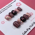 Glittered Heart press-on nails by CutiePop Nail Shop featuring short square-shaped nails in soft pink or nude tones, adorned with glitter accents and heart-shaped charms for a sweet and romantic finish.

