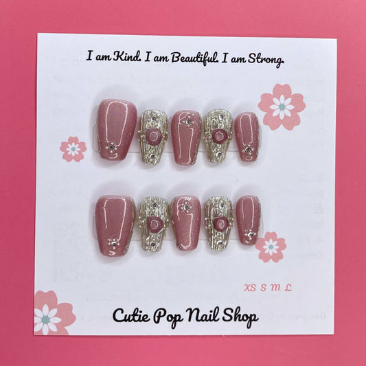 Gold Rosey press on nails by CutiePop Nail Shop featuring medium coffin shaped nails in a luxurious mix of rose gold and warm golden hues, enhanced with hand sculpted 3D gel accents and subtle metallic shimmer for an elegant and glamorous aesthetic.