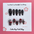 Gothic Delight press on nails by CutiePop Nail Shop featuring long coffin shaped nails painted in glossy jet black polish, accented with dark red duochrome shimmer and intricate gothic motifs like crosses or rose patterns, finished with subtle metallic or glitter highlights for a dramatic, dark romantic aesthetic.