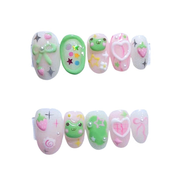 Kawaii Froggy press-on nails by CutiePop Nail Shop feature fun short round/oval-shaped nails in soft pastel greens and pinks. Each nail is decorated with playful hand-painted frog faces, strawberries, hearts, bows, and sparkly star accents—perfect for a whimsical, kawaii-inspired aesthetic. The set includes 10 reusable handmade nails, jelly adhesive tabs, a mini nail file, and a cuticle stick for easy, mess-free application.


