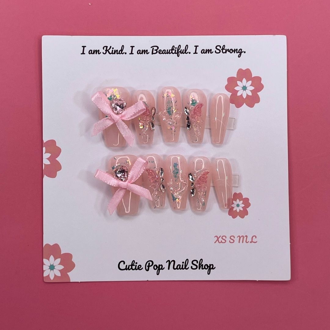 Lovely Butterfly press on nails by CutiePop Nail Shop featuring medium coffin shaped nails with a soft pastel base, adorned with a large 3D butterfly charm and delicate ribbon accents—designed for a dreamy and feminine look.

