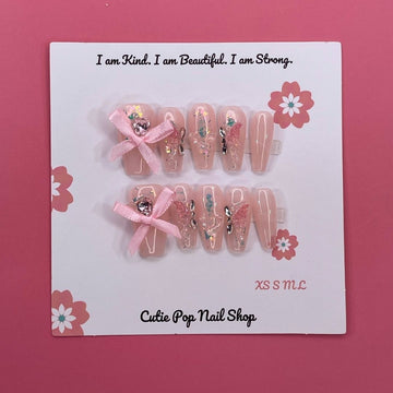Lovely Butterfly press on nails by CutiePop Nail Shop featuring medium coffin shaped nails with a soft pastel base, adorned with a large 3D butterfly charm and delicate ribbon accents—designed for a dreamy and feminine look.

