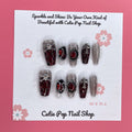 Rebel Chic press‑on nails by CutiePop Nail Shop featuring a medium‑length coffin-shaped set combining glossy jet-black, deep blood-red, and transparent nails accented with edgy skull motifs, mirrored stone embellishments, and stylized cross details—hand-painted and hand-sculpted for a bold, gothic-rock aesthetic.