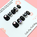 Short Kuromi press-on nails in a compact length with a soft color base, featuring 3D Kuromi character charms and cute kawaii-style accents, finished with a glossy shine – displayed on a Cutie Pop Nail Shop card.