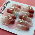 Soft Girly press‑on nails by CutiePop Nail Shop featuring medium-length coffin-shaped nails in a delicate blush pink tone with dainty rose-gold metallic accents, glitter gradient tips, and tiny bow motifs on accent nails. The kit includes 10 reusable handmade press-ons, jelly adhesive tabs, a mini nail file, and a cuticle stick—offering a soft, feminine, and elegant everyday look.