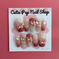 Soft Girly press‑on nails by CutiePop Nail Shop featuring medium-length coffin-shaped nails in a delicate blush pink tone with dainty rose-gold metallic accents, glitter gradient tips, and tiny bow motifs on accent nails. The kit includes 10 reusable handmade press-ons, jelly adhesive tabs, a mini nail file, and a cuticle stick—offering a soft, feminine, and elegant everyday look.