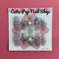 Star Gem (Blue) press on nails by CutiePop Nail Shop featuring medium coffin shaped nails in a translucent pale blue base adorned with sparkling silver star shaped gems and multicolored rhinestones for a celestial, glam star aesthetic. Includes a reusable adhesive tab set, a mini nail file, and a cuticle stick for full DIY application.