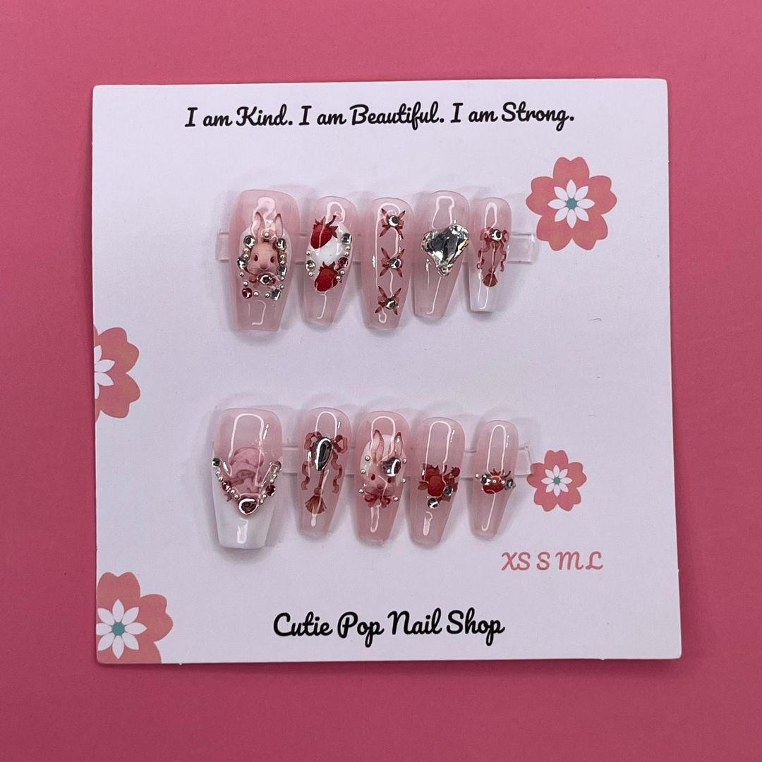 Strawberry Bunny press-on nails by CutiePop Nail Shop featuring medium-length coffin-shaped nails in soft pink tones with adorable strawberry and bunny designs. Accented with tiny bows, pearls, and glossy details for a sweet, kawaii-inspired aesthetic.

