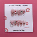 Strawberry Bunny press-on nails by CutiePop Nail Shop featuring medium-length coffin-shaped nails in soft pink tones with adorable strawberry and bunny designs. Accented with tiny bows, pearls, and glossy details for a sweet, kawaii-inspired aesthetic.

