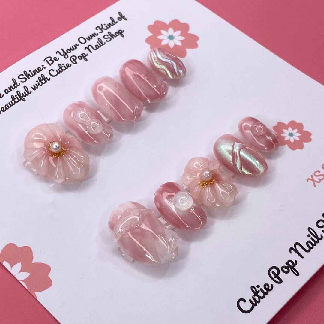 Sweet Pink press on nails by CutiePop Nail Shop featuring round shaped nails in soft pink tones, adorned with delicate flower designs and pearl centers for a cute and elegant finish.


