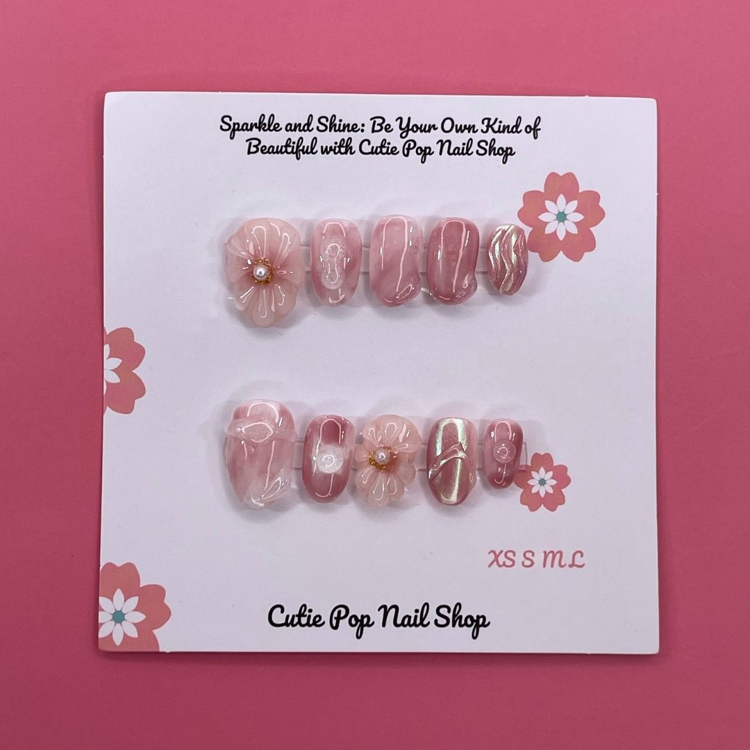 Sweet Pink press on nails by CutiePop Nail Shop featuring round shaped nails in soft pink tones, adorned with delicate flower designs and pearl centers for a cute and elegant finish.

